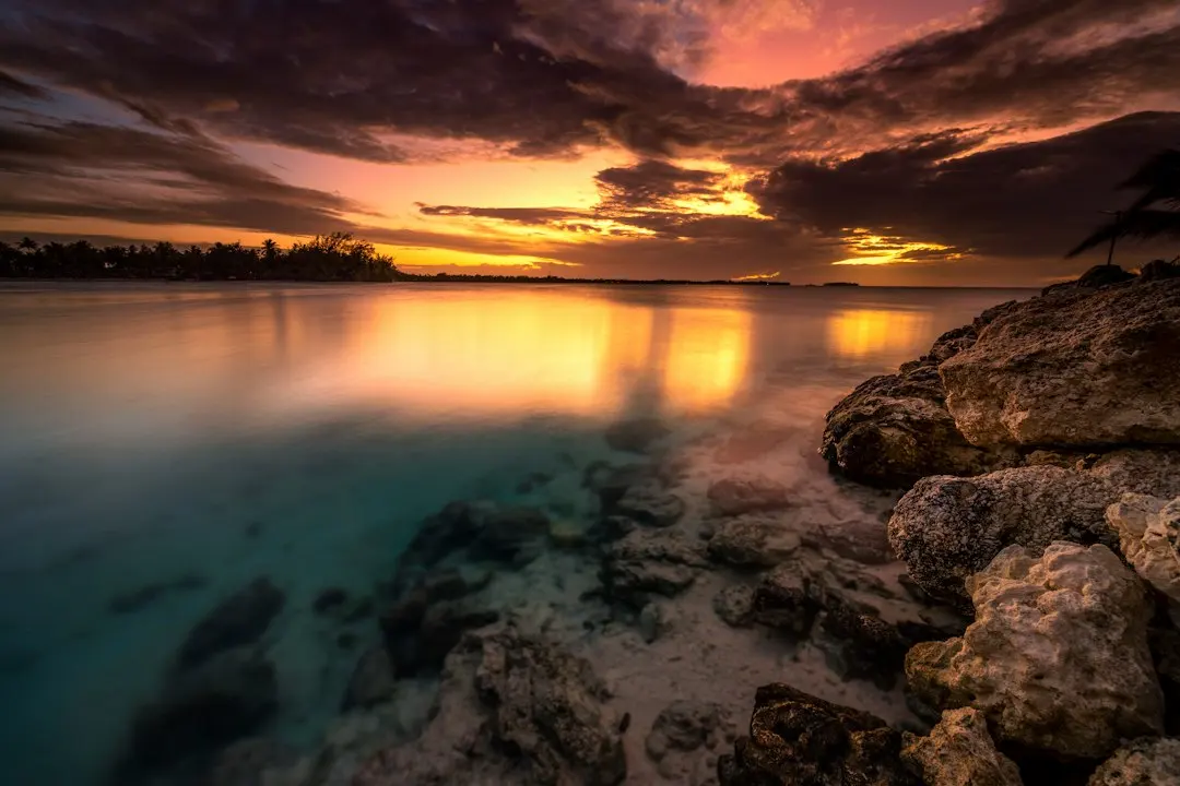 a beautiful sunset over the ocean with rocks